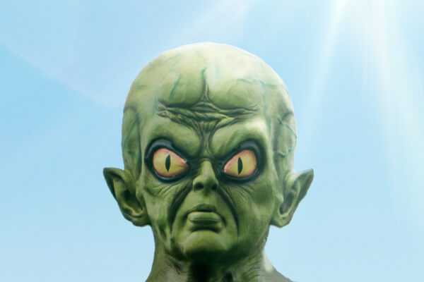 Un extraterrestre à la peau verte, aux grands yeux jaunes semblables à ceux d'un chat, aux oreilles pointues et au front ridé, se dresse sur un ciel bleu, la lumière du soleil entrant par le coin supérieur droit, comme s'il cherchait un réseau de communication.