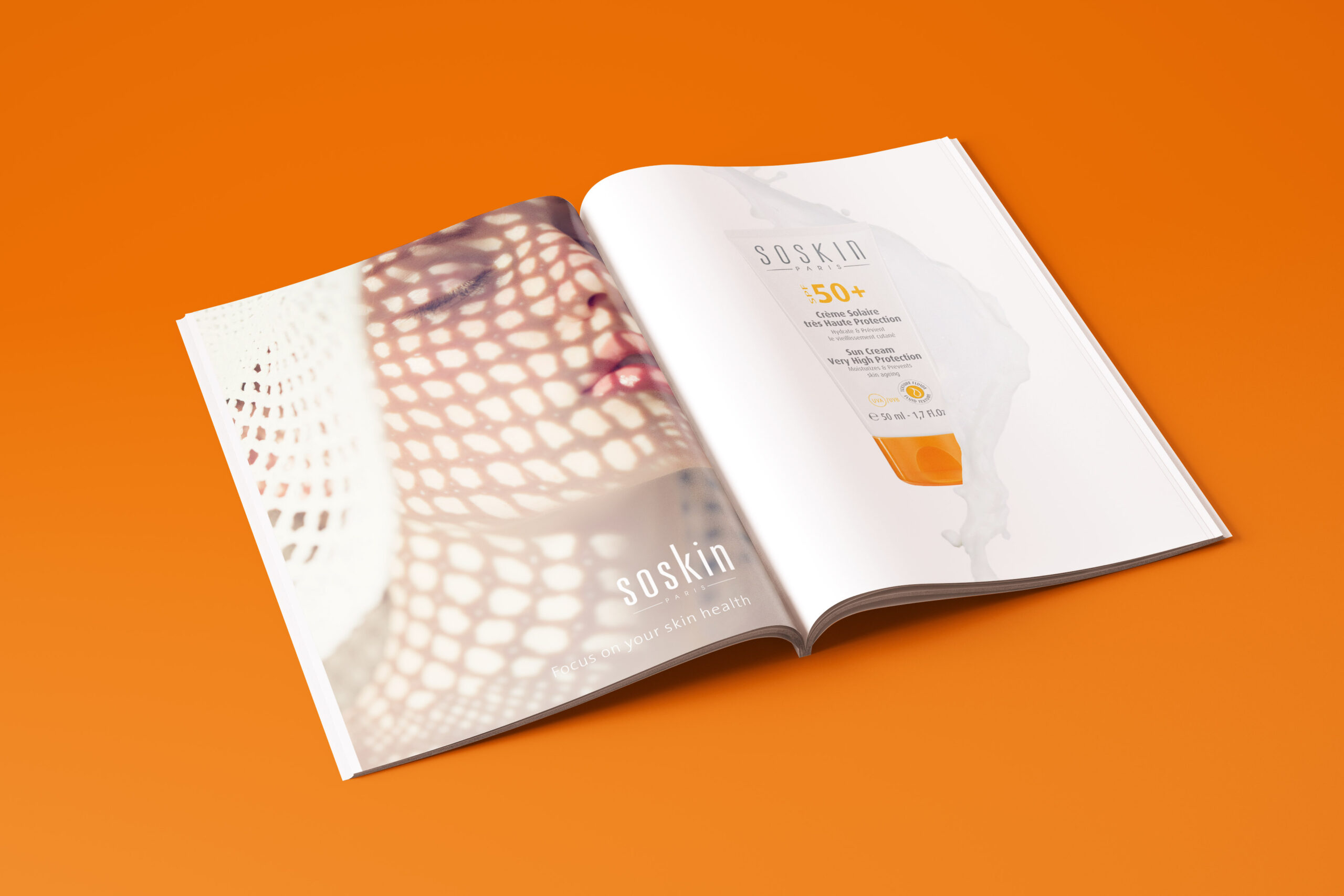 Magazine ouvert sur une publicité pour le soin de la peau Soskin, conçu pour la création de catalogue ; la page de gauche montre le visage d'une femme coiffée d'un chapeau de soleil qui projette une ombre en forme de filet, tandis que la page de droite présente un flacon de crème solaire Soskin SPF 50+ sur un fond blanc.
