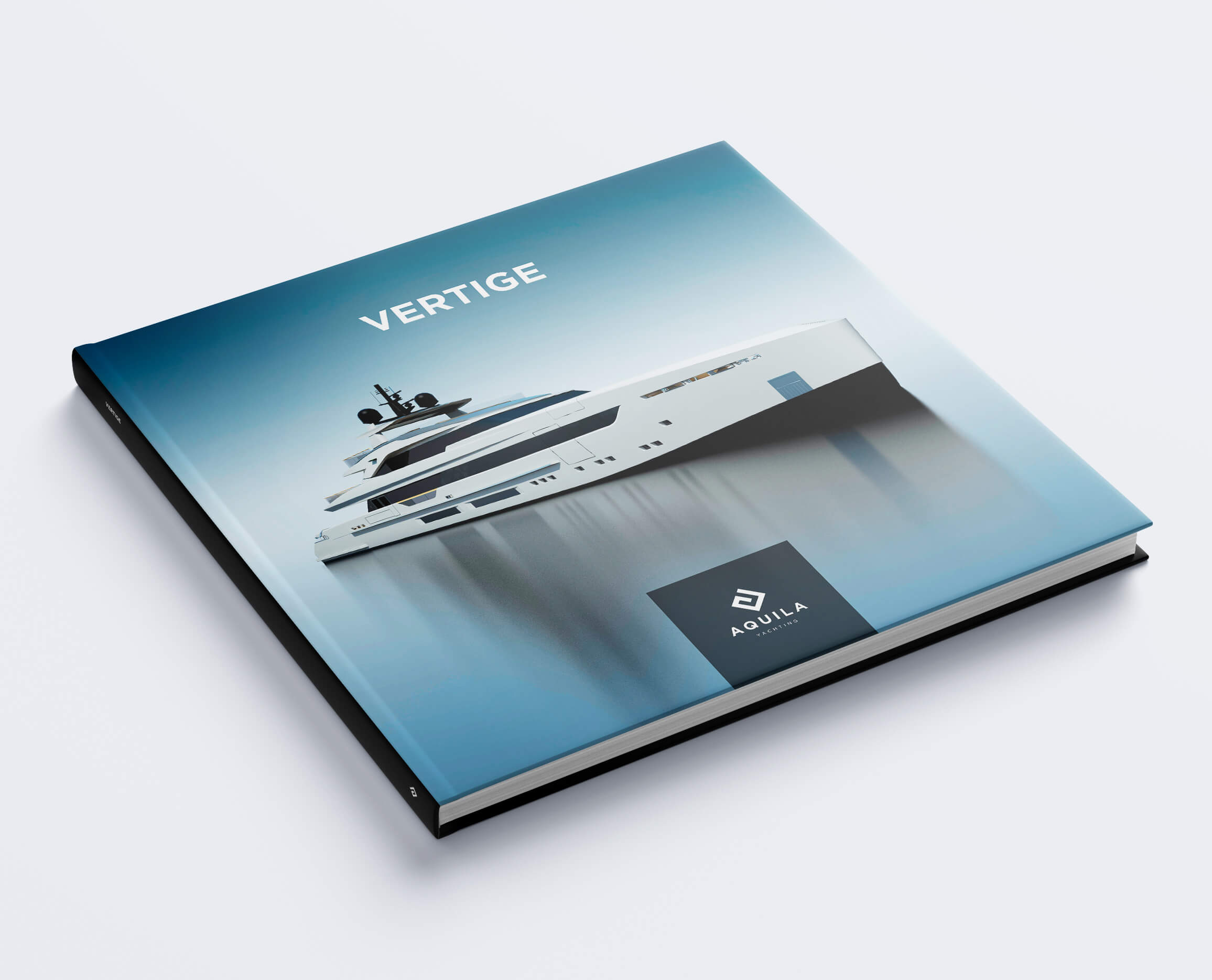 Un livre carré à couverture rigide intitulé "VERTIGE" présente un yacht blanc élégant sur une couverture bleue dégradée, avec le logo et la charte graphique d'Aquila affichés dans le coin inférieur droit. Le livre est présenté fermé sur un fond clair.
