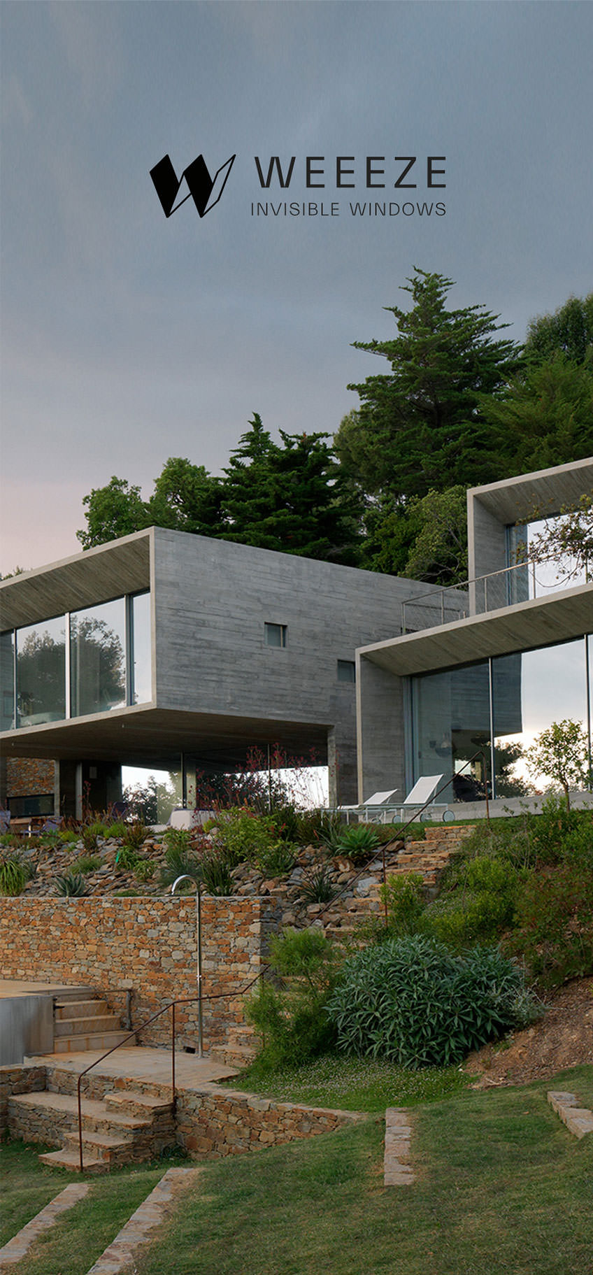Une maison moderne avec de grandes baies vitrées se trouve sur une colline paysagée avec des marches en pierre. Le logo "WEEEZE Invisible Windows" et la touche d'une Agence de communication BTP ajoutent de la sophistication. Des arbres et un ciel nuageux complètent la scène.