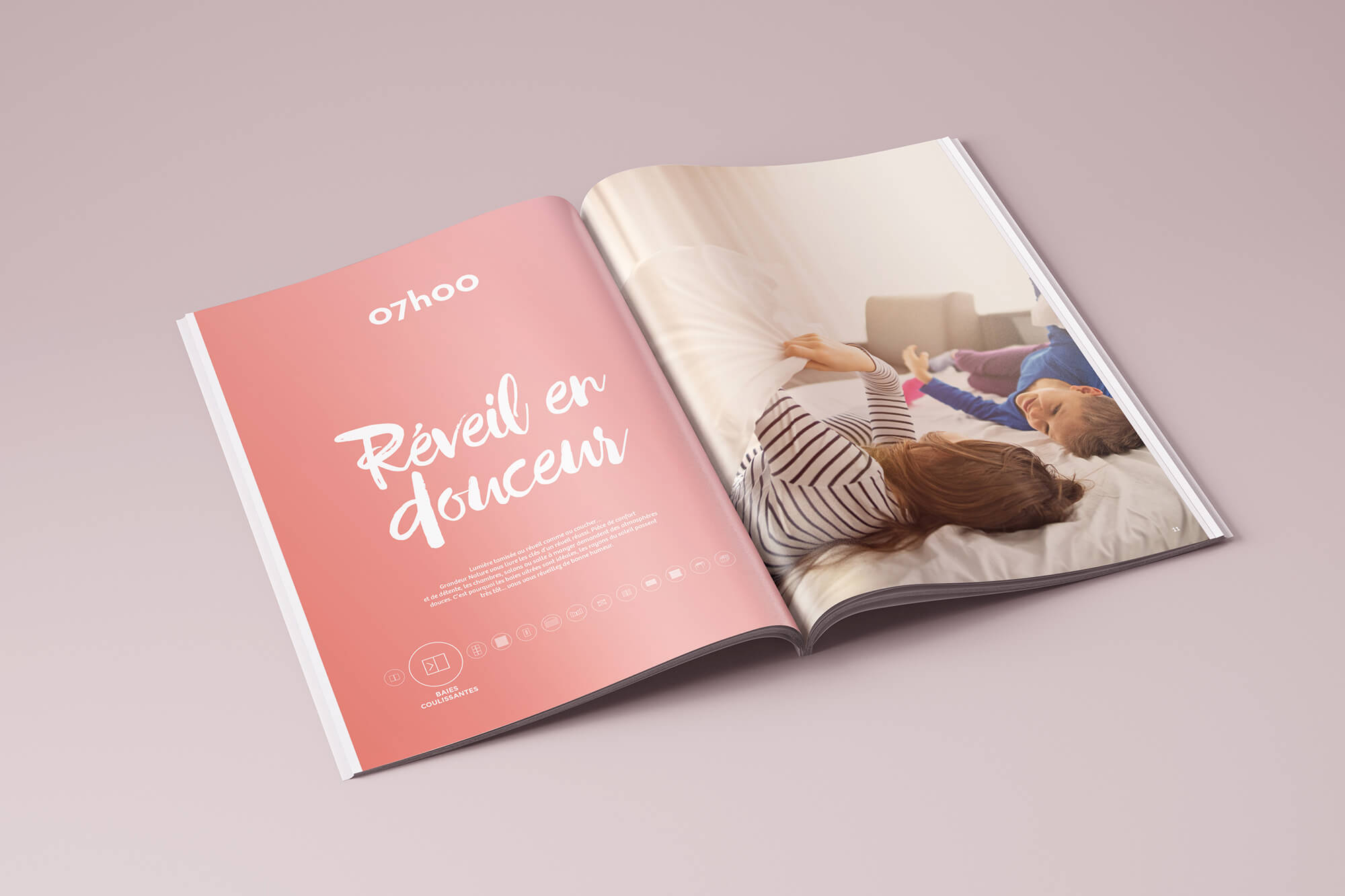 Un magazine ouvert Edition sur une surface rose affiche une page rose avec "07h00 Réveil en douceur" et une photo d'une femme et d'un enfant souriant et jouant ensemble dans leur chambre douillette.