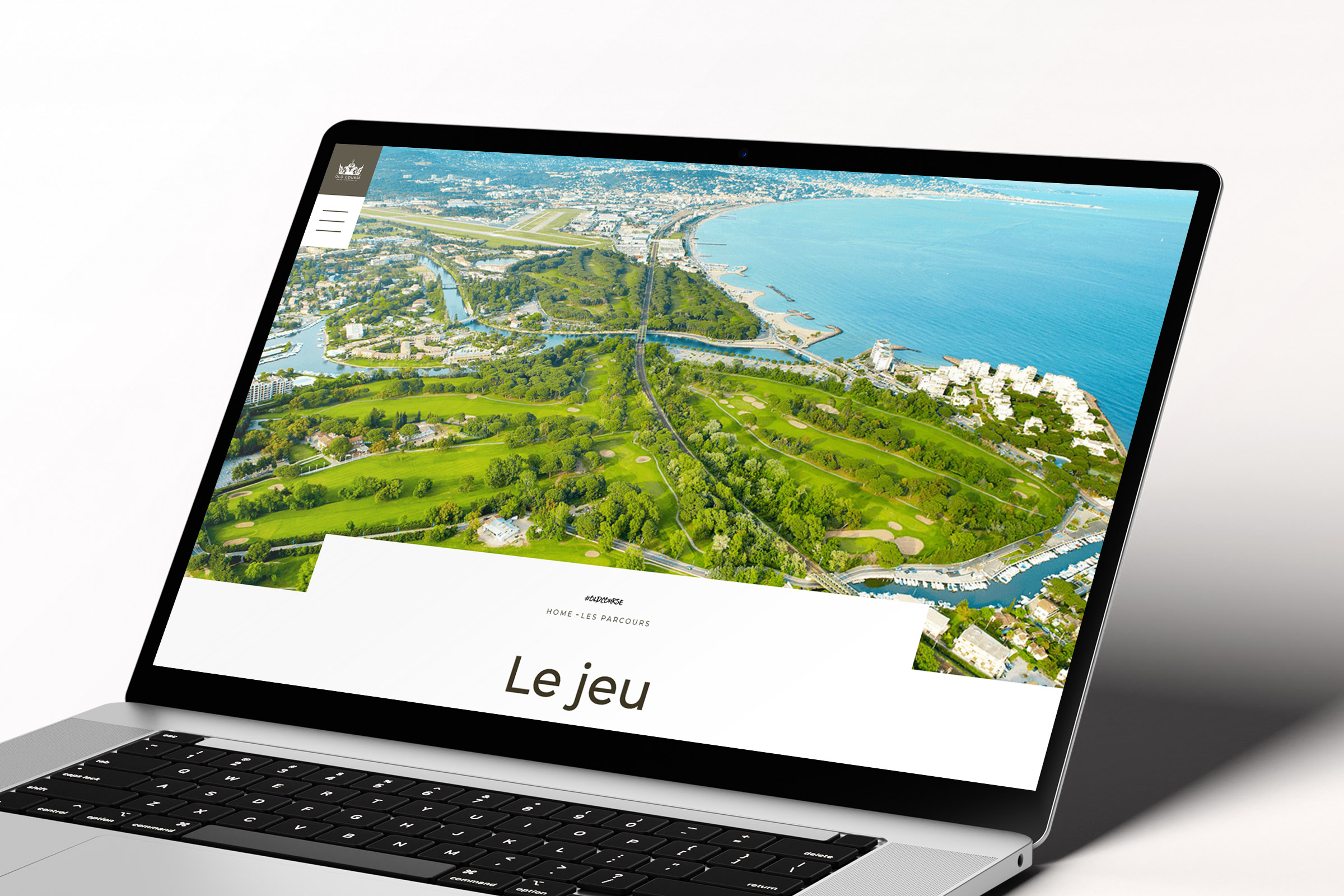 Un ordinateur portable affiche une création site web avec une vue aérienne d'un terrain de golf verdoyant au bord de la mer, avec la mer et le paysage urbain en arrière-plan et les mots "Le jeu" bien en évidence sur l'écran.
