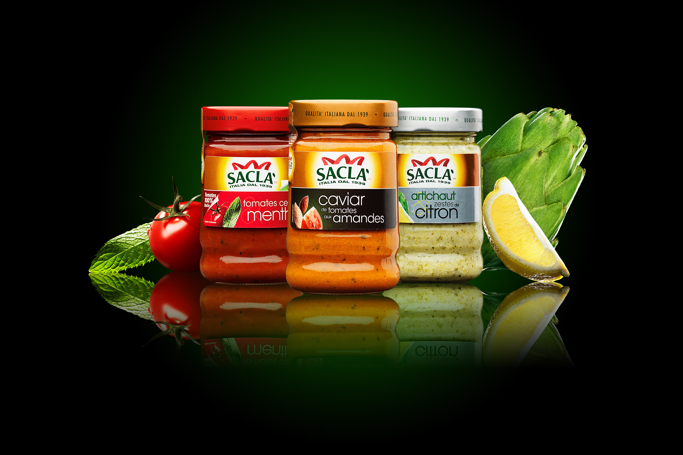 Trois pots de sauce Saclà, accompagnés d'ingrédients frais tels que tomates, poivrons rouges, amandes, artichauts et quartiers de citron, mettent en valeur une conception élégante de l'emballage sur un fond dégradé noir et vert avec des accents réfléchissants.