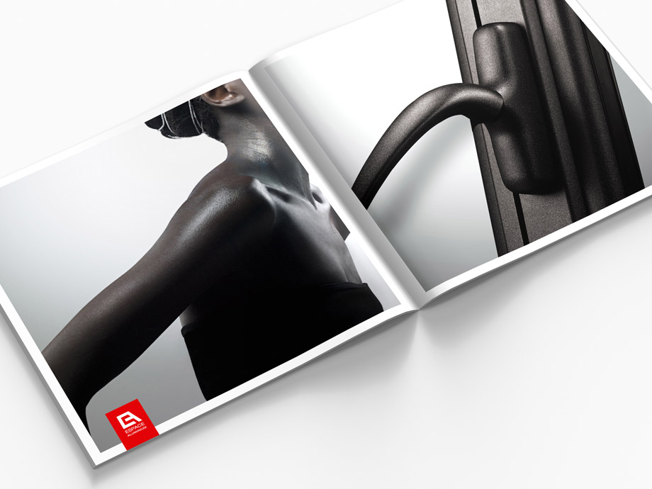 Un magazine ouvert révèle un gros plan d'une poignée métallique à droite et une image artistique et brillante d'un bras et d'une épaule nus à gauche, avec un petit logo rouge dans le coin - une inspiration parfaite pour tout projet de création charte graphique.