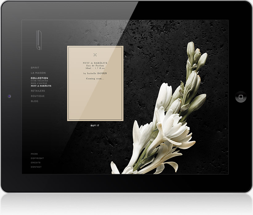 L'écran d'une tablette affiche la page d'un produit de parfum, conçue par une agence de communication digitale à Nice, avec une carte de couleur crème étiquetée "NUIT À BAZEL" et une composition florale blanche sur un fond noir texturé.