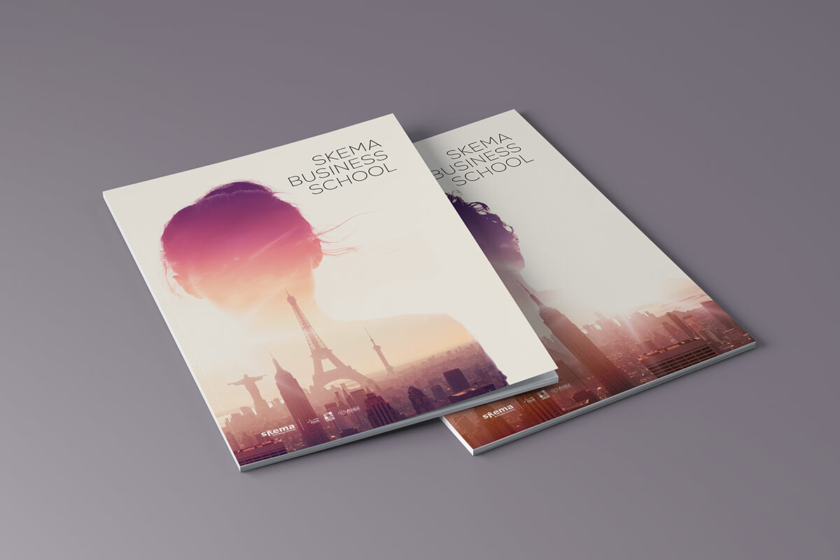 Deux brochures d'édition pour SKEMA Business School reposent sur une surface grise. Les couvertures présentent une double exposition de la silhouette d'une femme mélangée à un paysage urbain, mettant en évidence des points de repère tels que la Tour Eiffel.