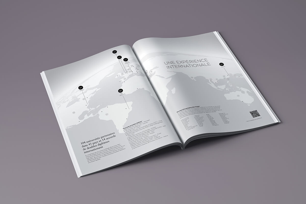 L'édition d'un magazine est ouverte sur une surface grise, affichant une carte du monde avec des repères noirs et un texte en français, y compris le titre "UNE EXPÉRIENCE INTERNATIONALE" sur la page de droite.