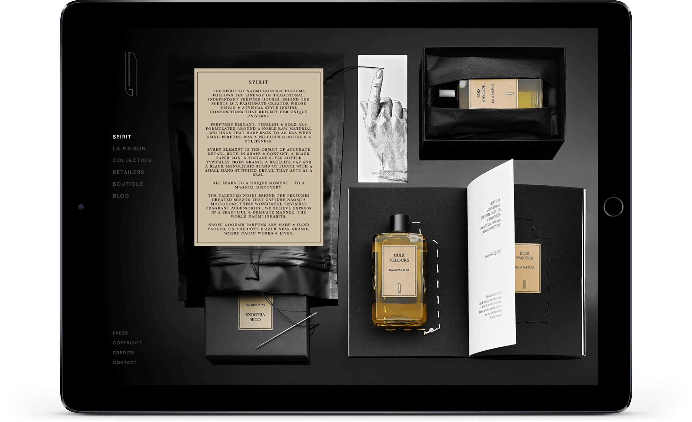 Une tablette ouverte affiche une mise en page avec une bouteille de parfum, un livre, une carte avec du texte, et plus encore - présentant des éléments de conception pour la création site internet sur un fond noir et blanc saisissant.