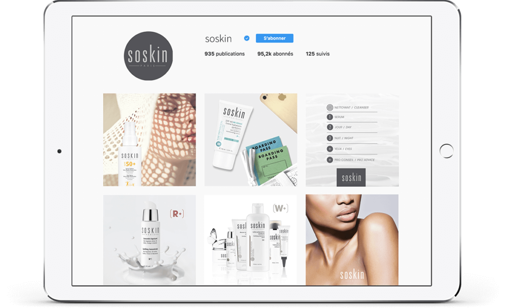Une tablette présente un profil Instagram pour « soskin », avec des produits de soin et un gros plan de l'épaule d'une personne. Grâce à une gestion communautaire experte, le profil compte un nombre impressionnant de 95,2 000 abonnés, créant ainsi un espace dynamique pour les passionnés de soins de la peau.