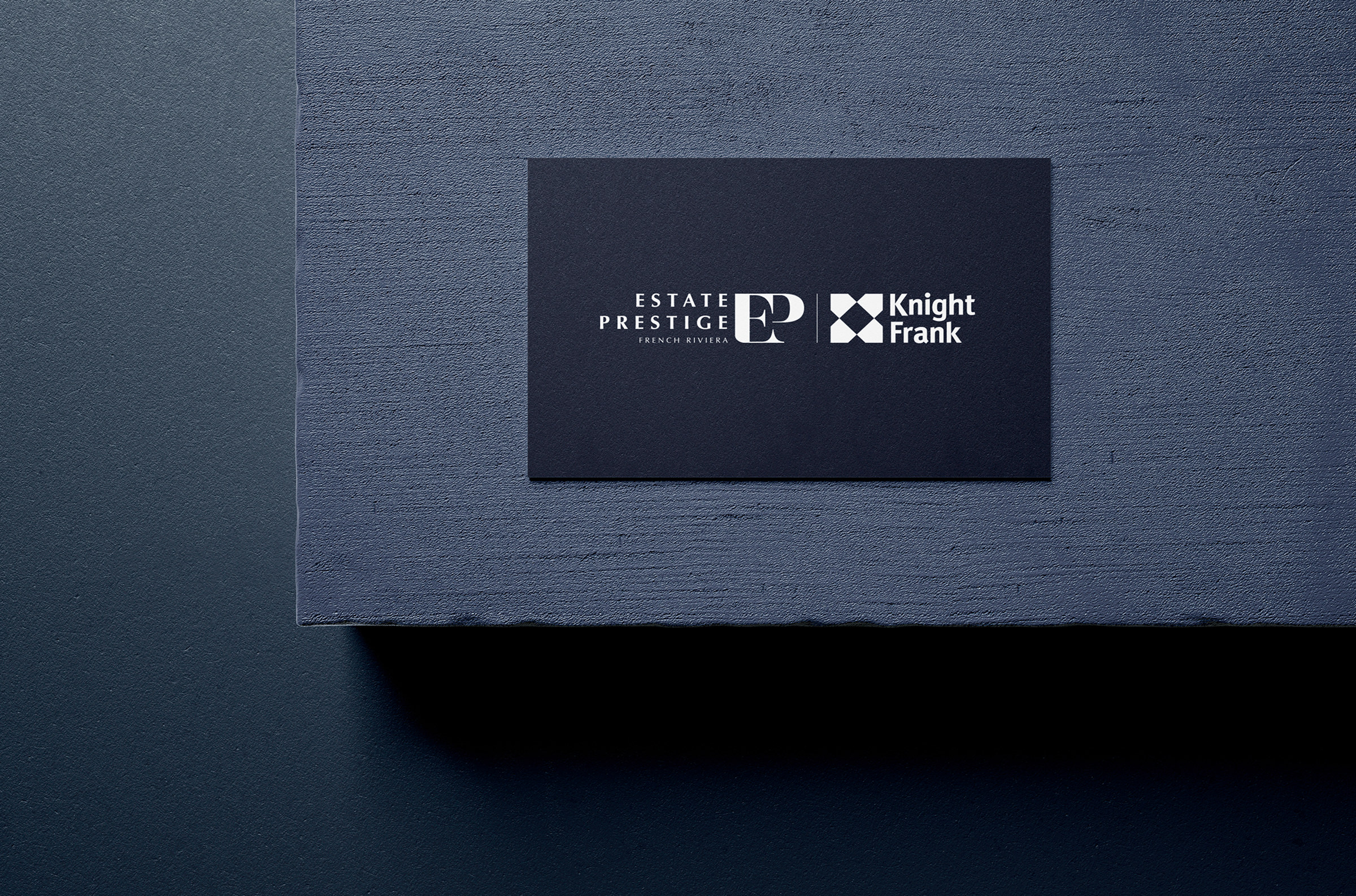 Une carte de visite de couleur sombre avec les mots "Estate Prestige", "PR French Riviera" et "Knight Frank" en blanc, sur une surface texturée bleu foncé - idéale pour mettre en valeur l'expertise en matière de développement de site web sur mesure.