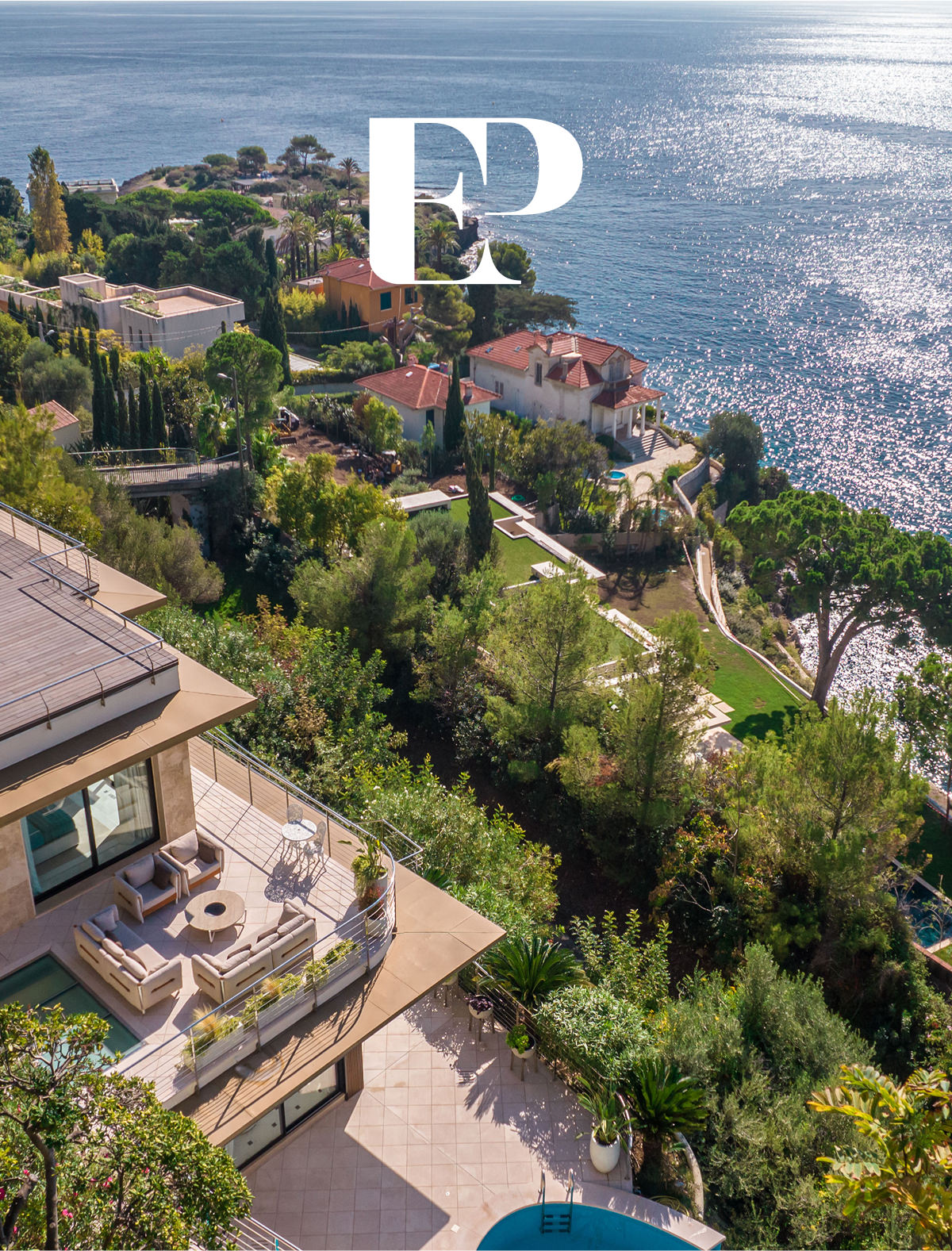 Vue aérienne d'une villa côtière moderne avec des terrasses spacieuses et des sièges, entourée d'une végétation luxuriante, surplombant la mer étincelante et les maisons voisines le long du rivage. Les lettres "EP" et "Développement de site web sur mesure" apparaissent en haut au centre.