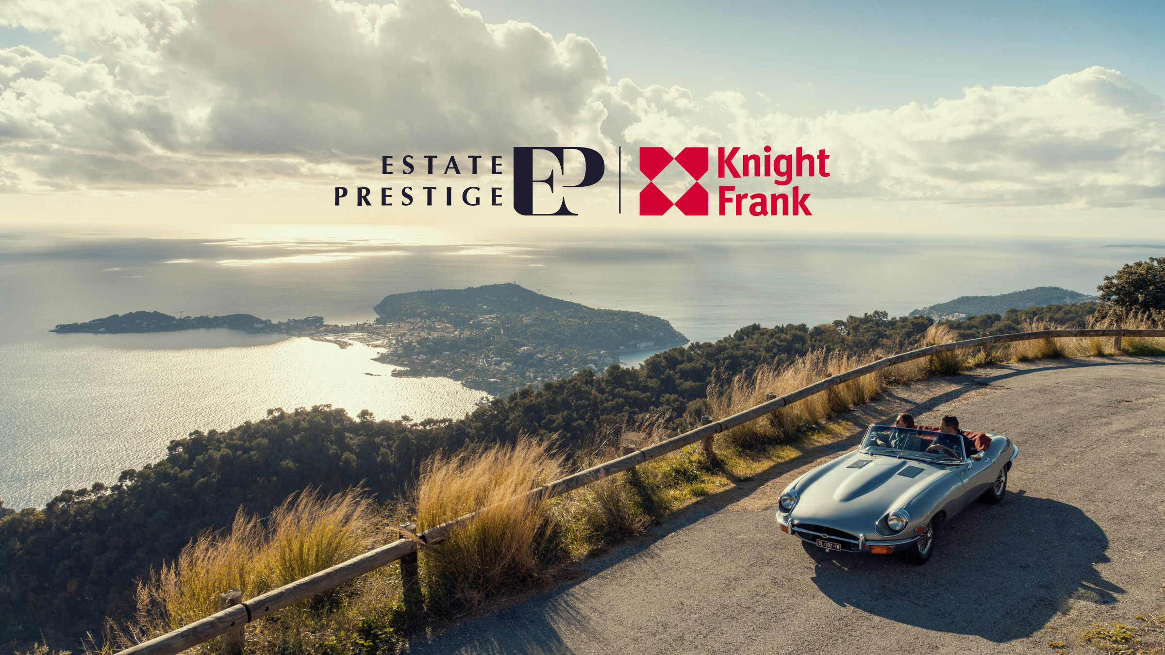 Une voiture décapotable classique roule sur une route de montagne côtière avec deux personnes à l'intérieur, surplombant une côte pittoresque. Les logos Estate Prestige et Knight Frank, ainsi que "Développement de site web sur mesure", apparaissent dans le ciel partiellement nuageux.